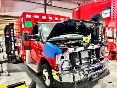 Ambulance undergoing remount service with chassis inspection and mechanical upgrades to extend EMS fleet life.