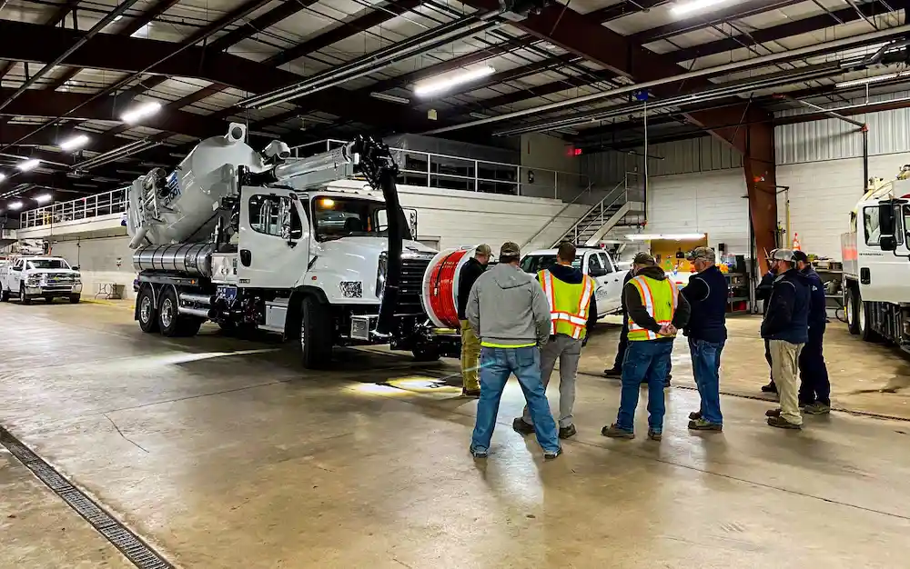 Group of employees participating in hands-on equipment training, learning operational procedures, safety practices, and proper machine use in a field environment.